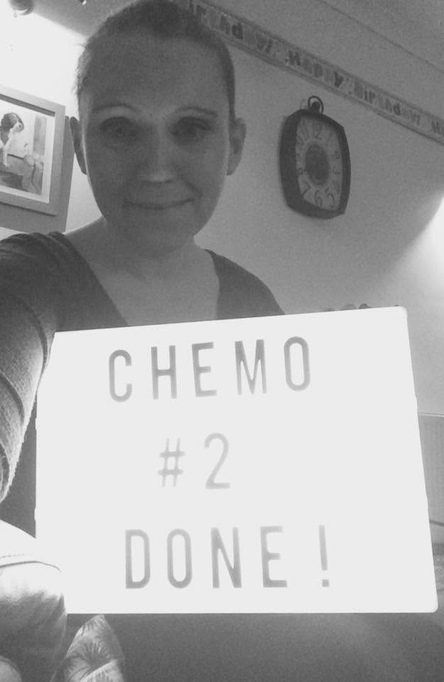 Karma holding a sign that reads Chemo #2 Done